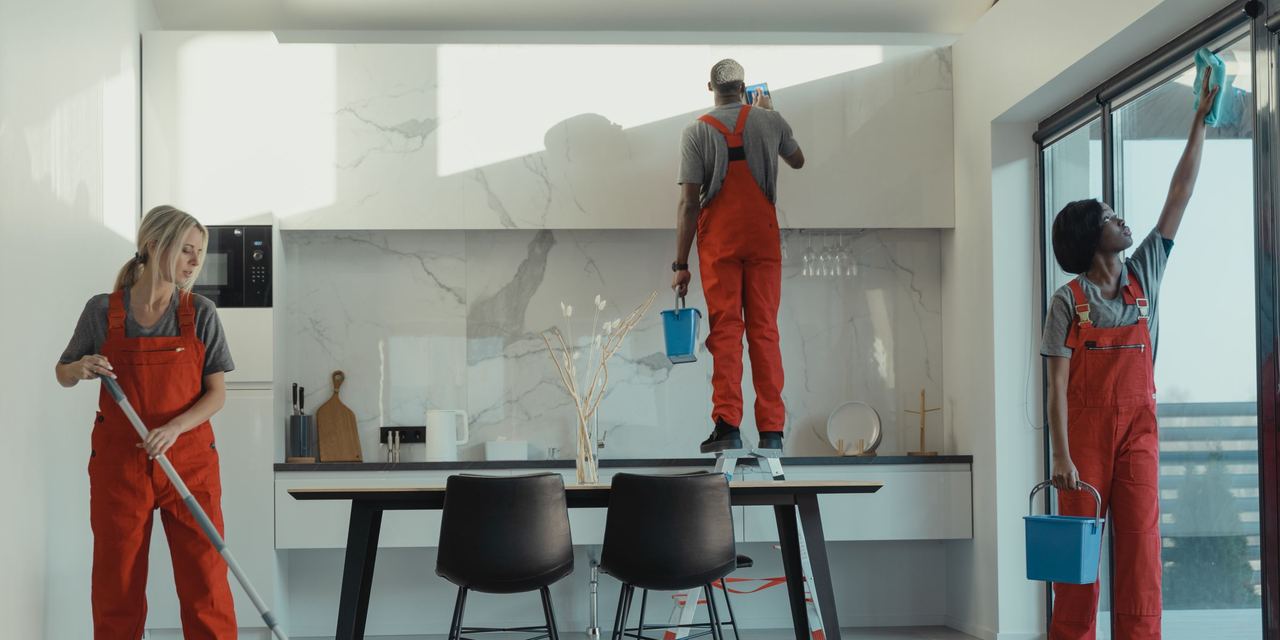 Uniformed cleaning crew mopping, wiping glass and dusting in a bright modern workspace